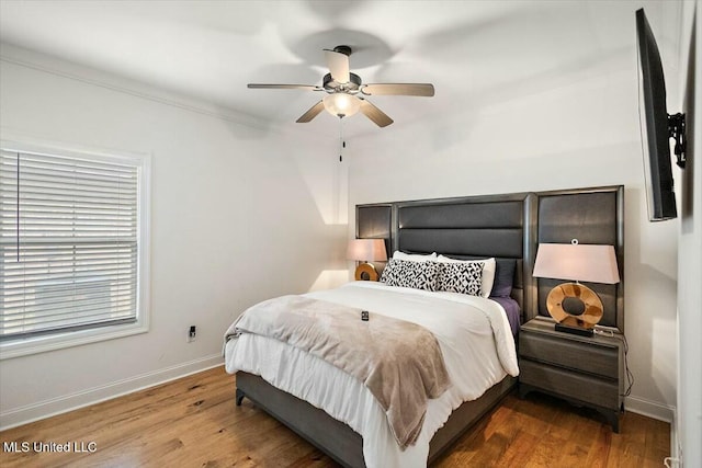 bedroom with ornamental molding, ceiling fan, baseboards, and wood finished floors