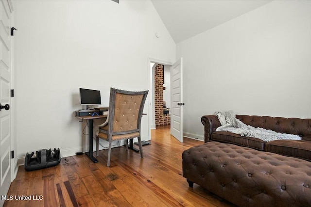 office area featuring high vaulted ceiling, wood-type flooring, and baseboards