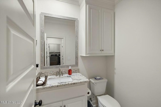 bathroom featuring washer / dryer, vanity, and toilet