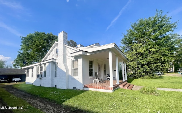 58 Snider St, Grenada, MS 38901 - view of side of home featuring a chimney, covered porch, a lawn, brick siding, and crawl space