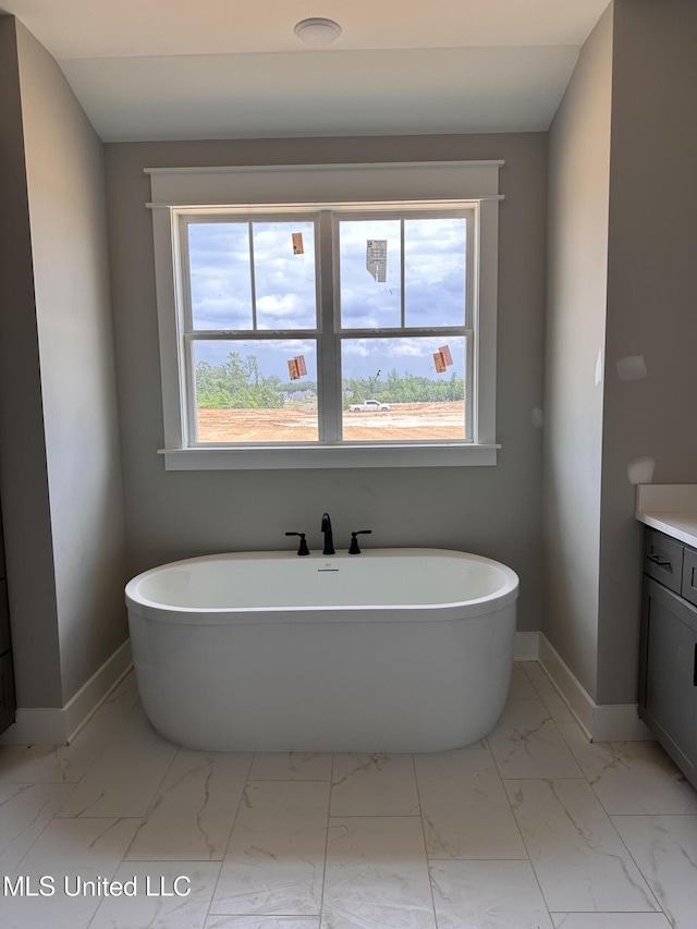 1740 Bakersfield Way, Nesbit, MS 38651 - bathroom with marble look tile flooring, vanity, a freestanding tub, and baseboards