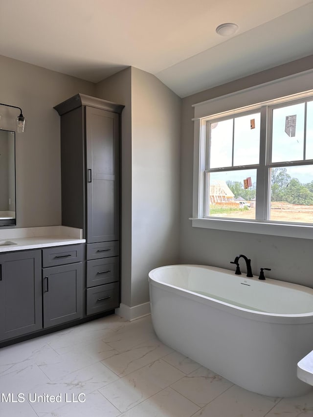 1740 Bakersfield Way, Nesbit, MS 38651 - bathroom with marble look tiles, vanity, a soaking tub, and baseboards