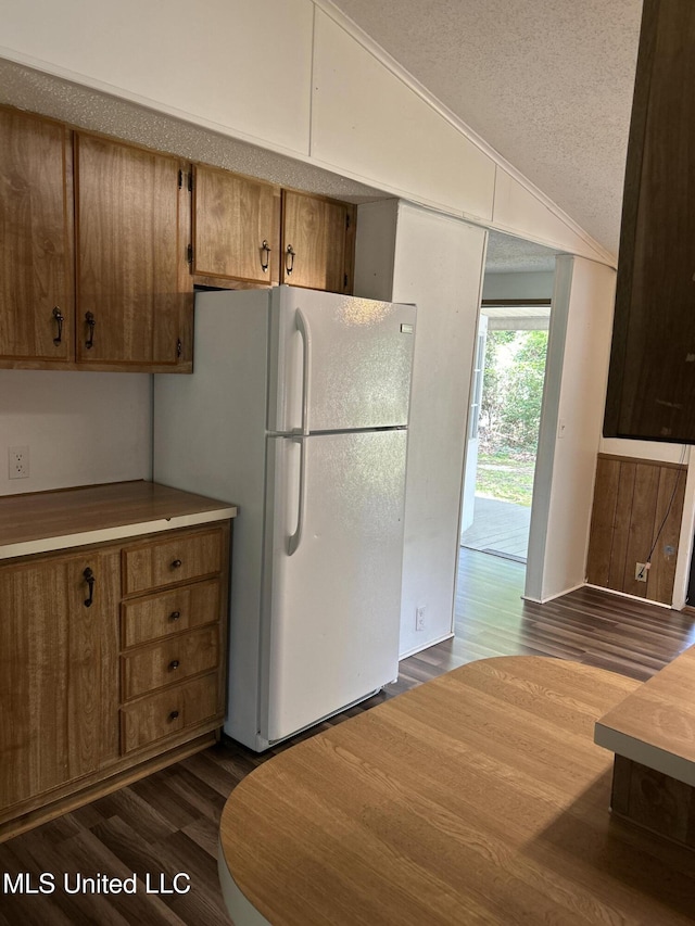 97131 Kapalama Dr, Diamondhead, MS 39525 - kitchen with lofted ceiling, freestanding refrigerator, dark wood finished floors, a textured ceiling, and brown cabinetry