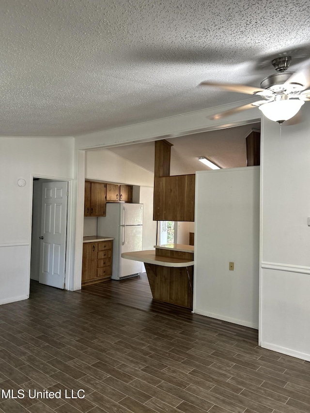 97131 Kapalama Dr, Diamondhead, MS 39525 - kitchen featuring freestanding refrigerator, dark wood finished floors, lofted ceiling, light countertops, and a textured ceiling