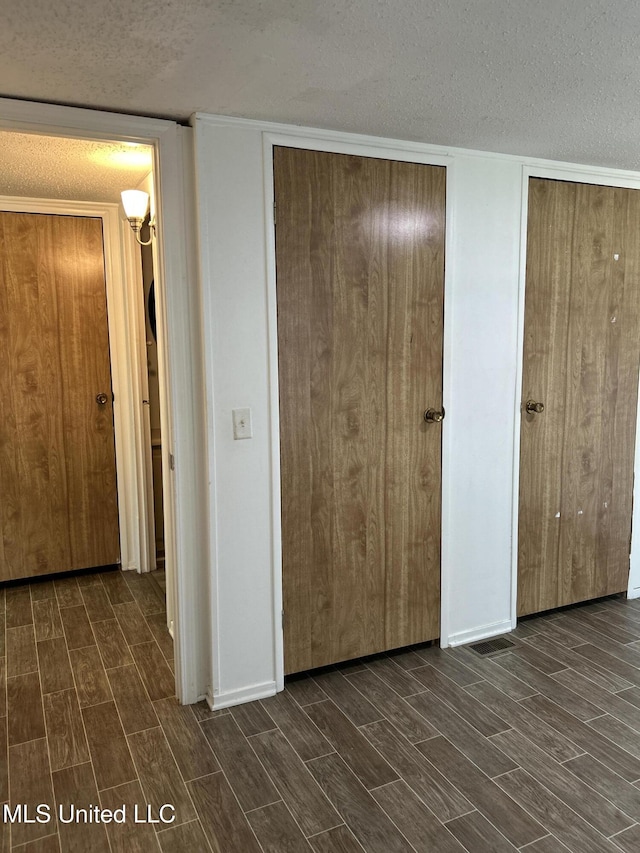 97131 Kapalama Dr, Diamondhead, MS 39525 - unfurnished bedroom with a textured ceiling, wood finish floors, and two closets