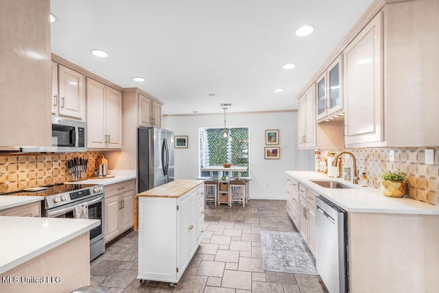 kitchen with appliances with stainless steel finishes, decorative light fixtures, butcher block counters, sink, and a center island