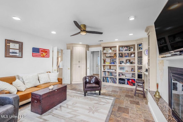 living room featuring ceiling fan and a high end fireplace