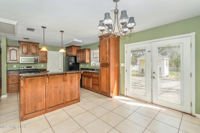 kitchen with visible vents, a sink, stainless steel appliances, dark countertops, and brown cabinets