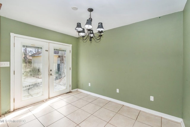 unfurnished dining area featuring light tile patterned floors, french doors, baseboards, and a chandelier