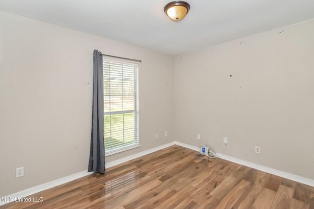 unfurnished room featuring baseboards and wood finished floors