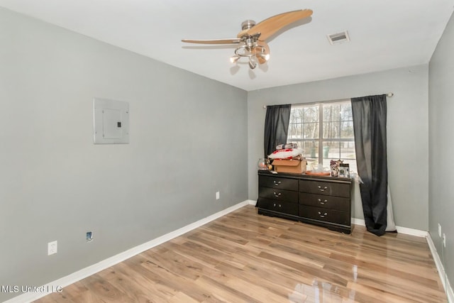 bedroom with electric panel, visible vents, baseboards, and light wood-style floors