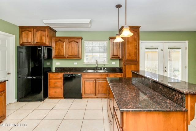 kitchen featuring light tile patterned floors, brown cabinets, hanging light fixtures, black appliances, and a sink