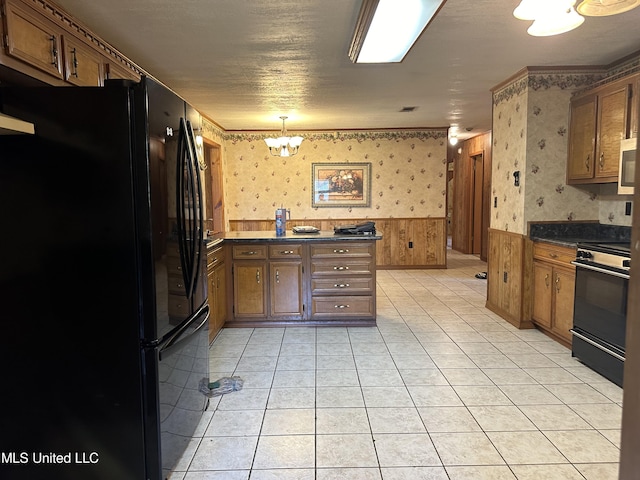 kitchen with range, a wainscoted wall, dark countertops, wallpapered walls, and freestanding refrigerator
