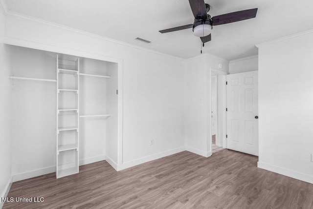 unfurnished bedroom with crown molding, wood-type flooring, a closet, and ceiling fan