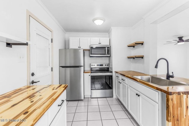 kitchen featuring wood counters, stainless steel appliances, sink, and white cabinets