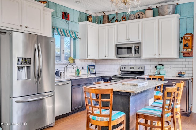 253 Sycamore St, Bay Saint Louis, MS 39520 - kitchen with decorative backsplash, light wood-style floors, white cabinets, a sink, and stainless steel appliances