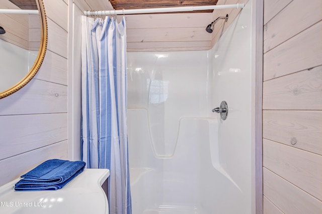 bathroom featuring wood walls and a shower with shower curtain