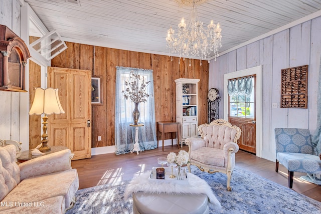 living room featuring a notable chandelier, wood-type flooring, and wooden walls