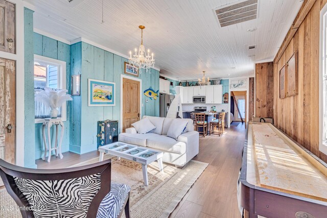 253 Sycamore St, Bay Saint Louis, MS 39520 - living area featuring visible vents, wood walls, crown molding, light wood-type flooring, and a chandelier