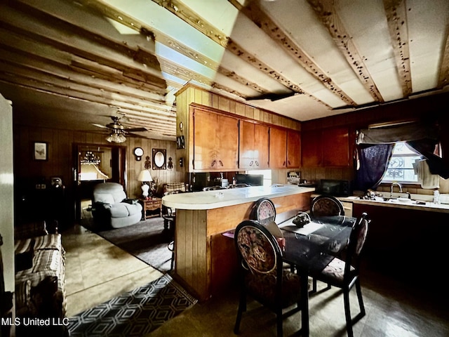 kitchen featuring light countertops, wooden walls, a peninsula, open floor plan, and ceiling fan