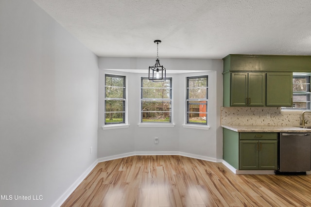 unfurnished dining area with a textured ceiling, plenty of natural light, and light hardwood / wood-style flooring