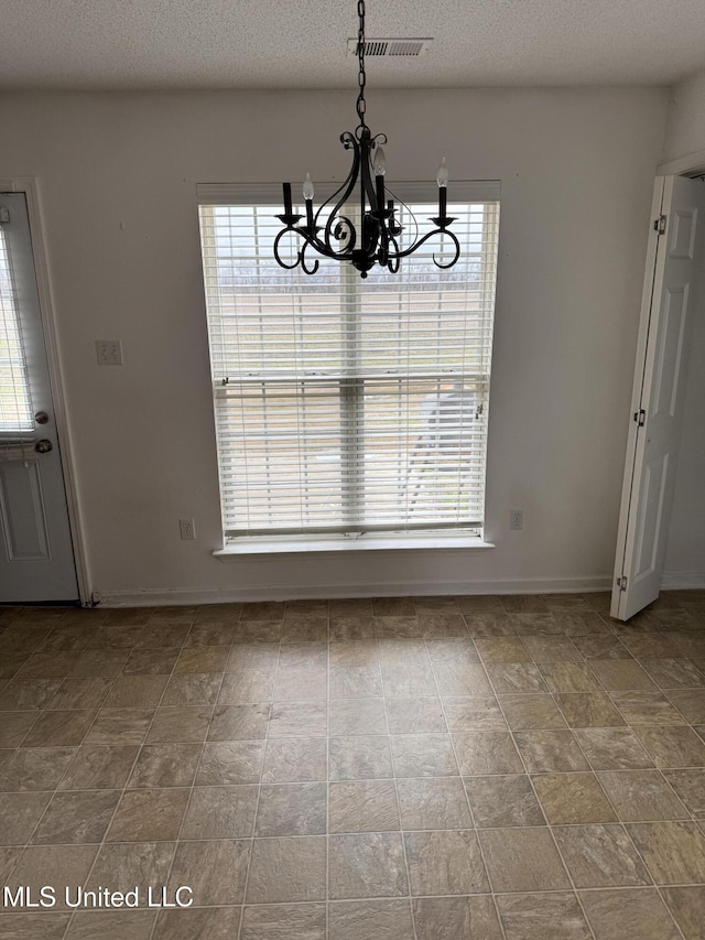 unfurnished dining area with a textured ceiling and a notable chandelier