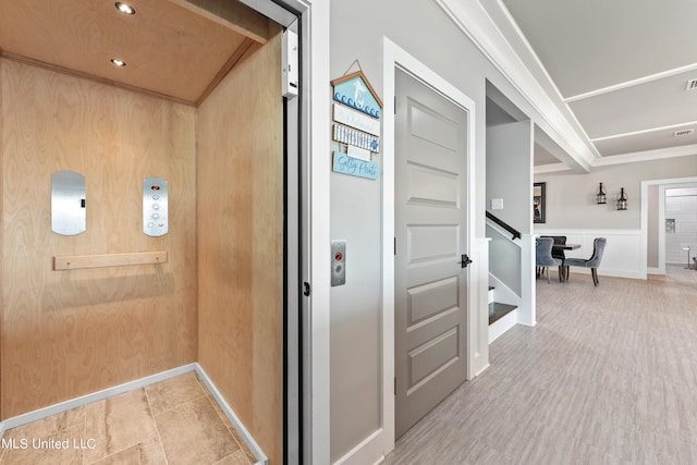 hallway with crown molding, hardwood / wood-style flooring, wooden walls, and elevator