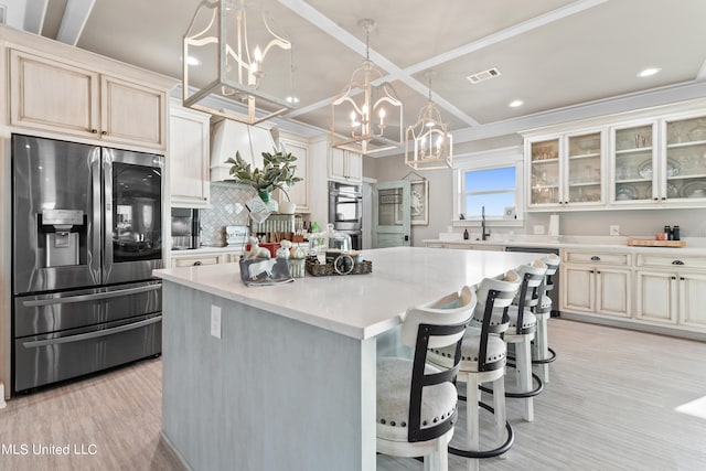 kitchen featuring tasteful backsplash, a kitchen island, light hardwood / wood-style flooring, crown molding, and stainless steel appliances