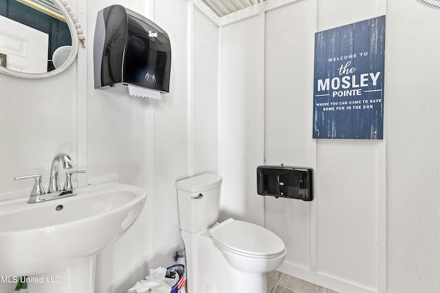 bathroom featuring toilet, tile patterned floors, and sink