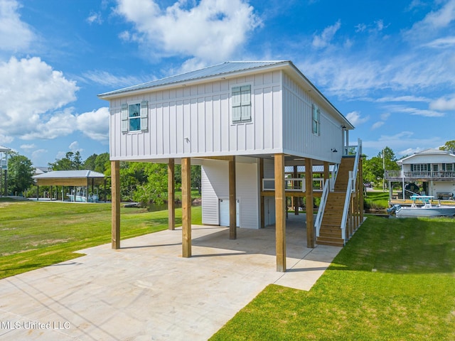 4054 Mallard St, Bay Saint Louis, MS 39520 - rear view of property with a carport, board and batten siding, stairs, concrete driveway, and a yard