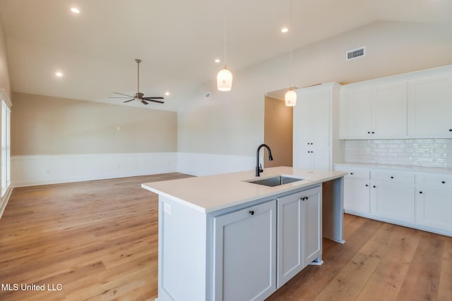 4054 Mallard St, Bay Saint Louis, MS 39520 - kitchen with a sink, vaulted ceiling, white cabinetry, an island with sink, and light wood-style floors