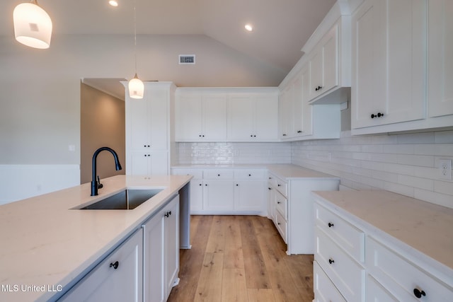 4054 Mallard St, Bay Saint Louis, MS 39520 - kitchen featuring a sink, white cabinetry, backsplash, vaulted ceiling, and light wood-style flooring