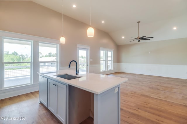 4054 Mallard St, Bay Saint Louis, MS 39520 - kitchen featuring a sink, wainscoting, lofted ceiling, light wood finished floors, and a center island with sink