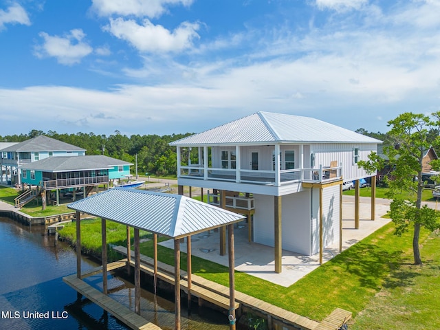 4054 Mallard St, Bay Saint Louis, MS 39520 - rear view of house with a water view, metal roof, boat lift, a patio, and a lawn