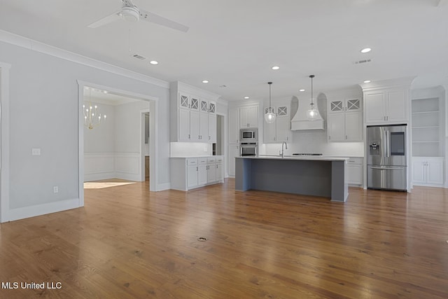 kitchen with white cabinets, appliances with stainless steel finishes, wood finished floors, light countertops, and crown molding