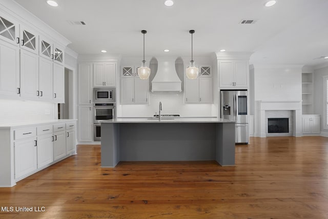 kitchen with white cabinets, premium range hood, visible vents, and stainless steel appliances