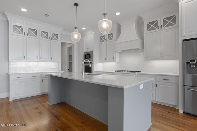 kitchen with stainless steel appliances, a sink, white cabinetry, and custom range hood