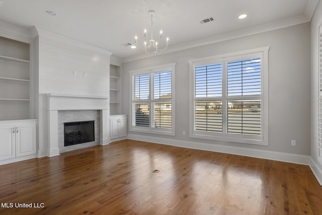 unfurnished living room with baseboards, wood finished floors, visible vents, and crown molding