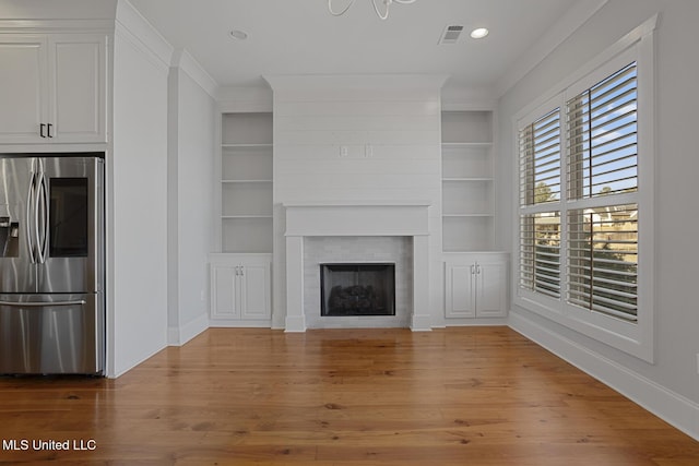 unfurnished living room featuring visible vents, wood finished floors, built in shelves, a fireplace, and recessed lighting