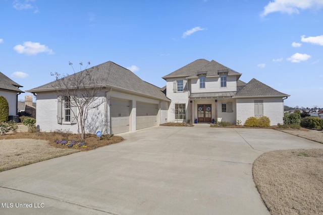 view of front of house featuring a garage, roof with shingles, and driveway