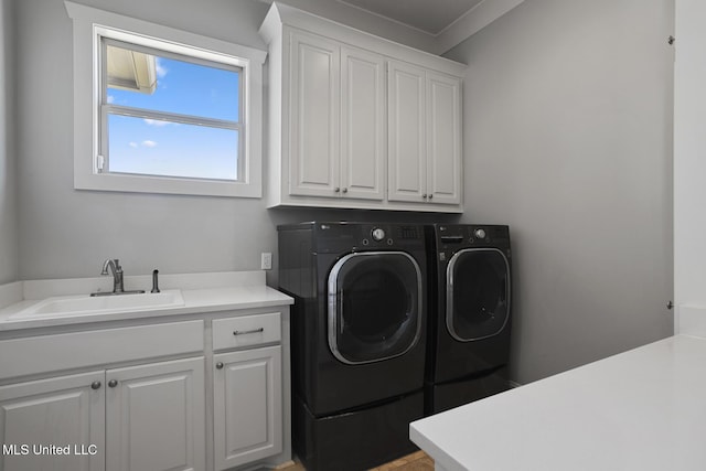 clothes washing area with cabinet space, a sink, and separate washer and dryer