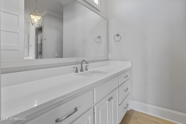 bathroom with a shower with shower door, wood finished floors, vanity, and baseboards