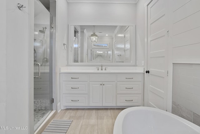 full bath featuring a stall shower, wood finish floors, a freestanding bath, and vanity