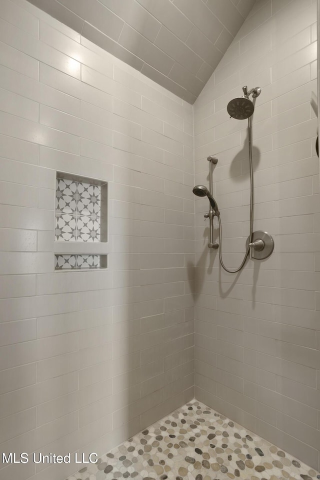 bathroom featuring vaulted ceiling and tiled shower