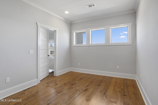 unfurnished bedroom with multiple windows, visible vents, wood finished floors, and ornamental molding