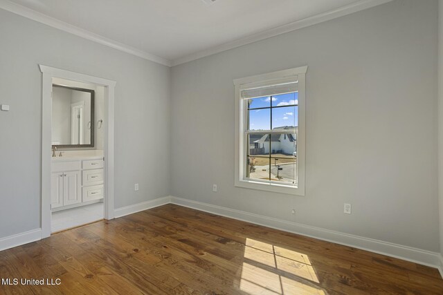 unfurnished bedroom with crown molding, connected bathroom, baseboards, and wood finished floors