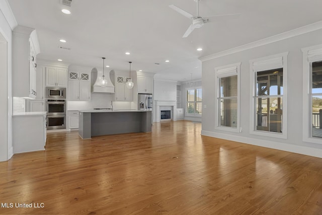 unfurnished living room featuring ceiling fan, recessed lighting, baseboards, light wood-style floors, and ornamental molding