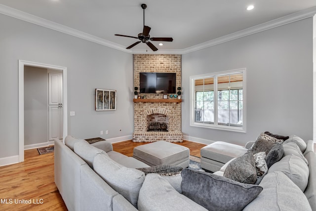 living room with crown molding, a brick fireplace, ceiling fan, and light hardwood / wood-style flooring