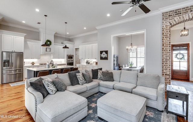 living room featuring ceiling fan with notable chandelier, light hardwood / wood-style flooring, and ornamental molding