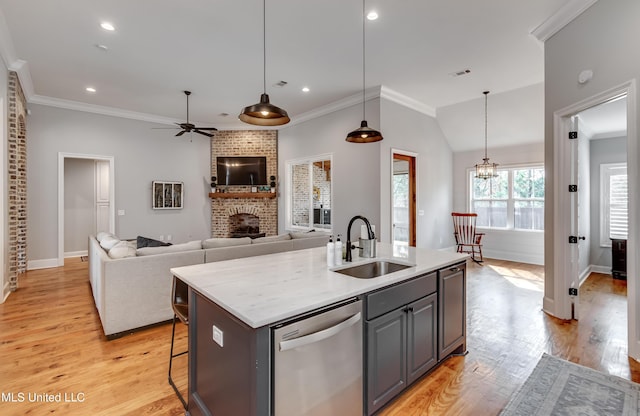 kitchen featuring sink, stainless steel dishwasher, an island with sink, pendant lighting, and a fireplace